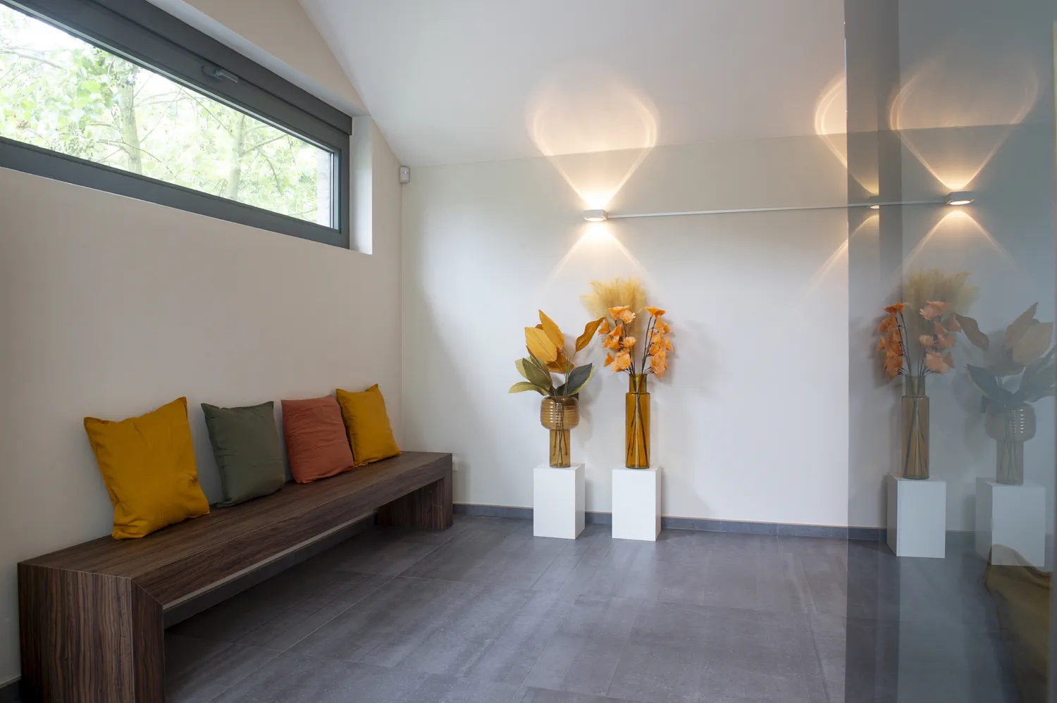 Ontvangstruimte met houten bank en kussens in aardetinten